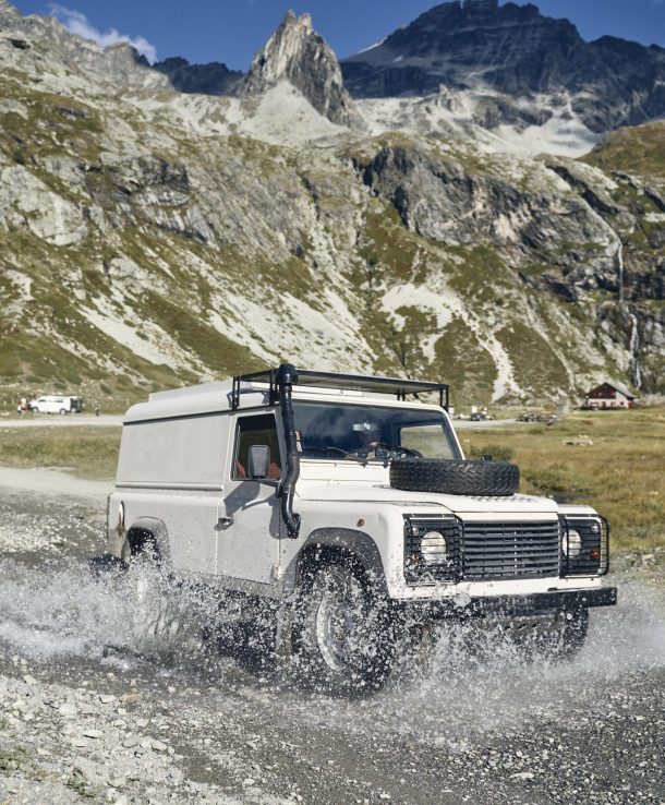 Woman with off-road vehicle driving through water by mountains on sunny day